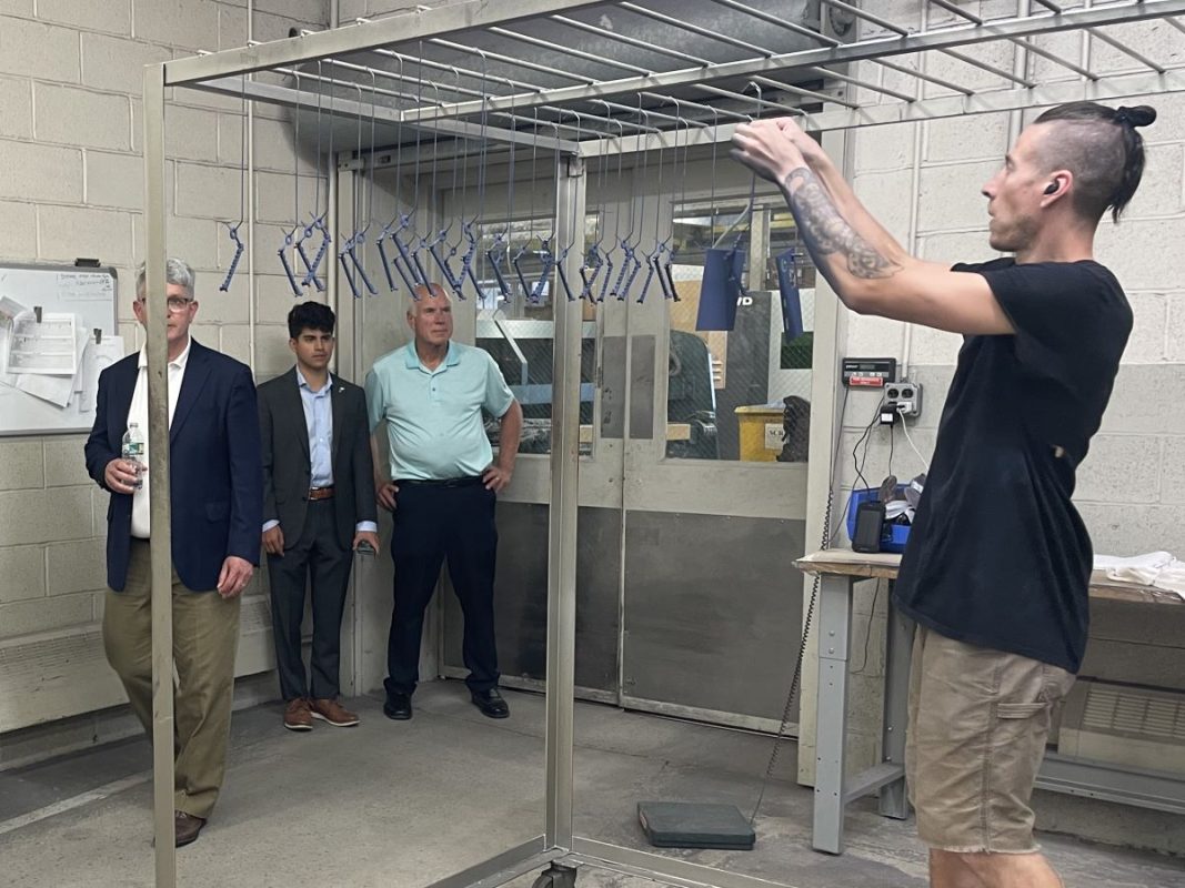 Sean hangs products to dry as Congressman Williams tours the facility.