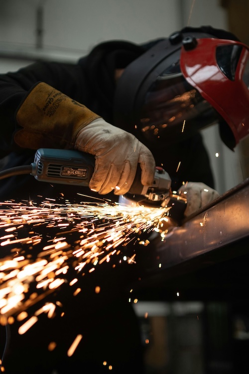 metal fabrication worker grinding down metal