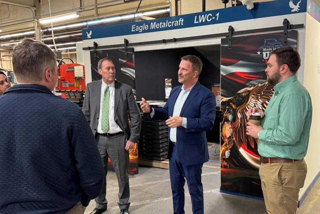 Michael Bower (center) speaks with regional partners on the shop floor during the Strategic Growth Services launch, highlighting the realities of scaling a manufacturing operation.