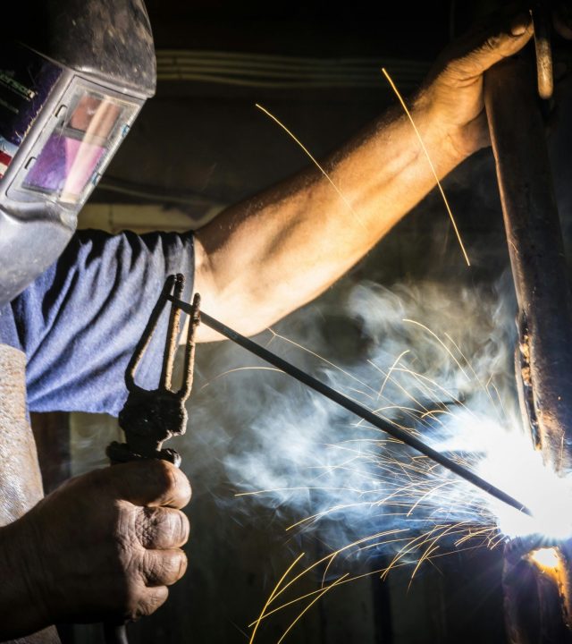 Close-up of a welder in action, showcasing bright sparks and metalworking skill indoors.